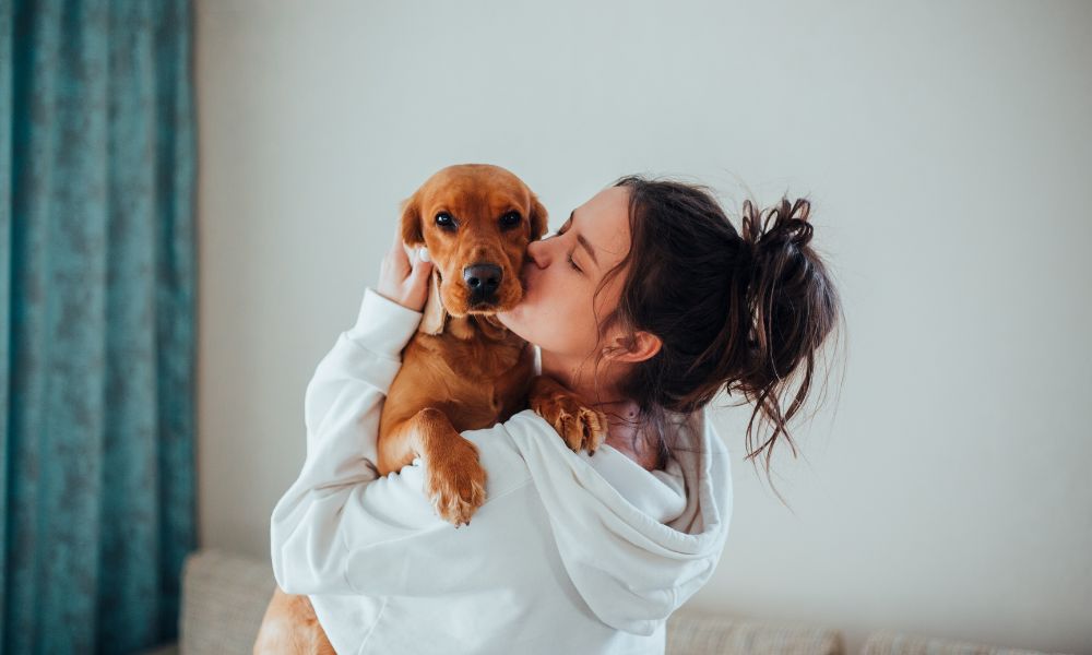 Lady pet sitter cuddling a dog.