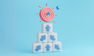 Arrows on building blocks leading to a target to represent achieving business goals.